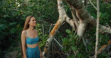 Gün batımında yoğun tropikal sulak arazide aşk dolu kırmızı mangrov ağacının kabuğuna hafifçe dokunan kadın..