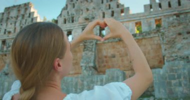 Mayan harabelerinin önünde elleri ile kalp şekli oluşturan kadın..