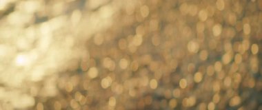 Altın ışık yazın kumsaldaki çakıl taşlarına yansıyor ve alacakaranlıkta bokeh etkisi var..