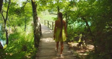 Yaz günü Plitvice Gölleri Ulusal Park Ormanı 'nda tahta bir patikada yürüyen bir kadın..