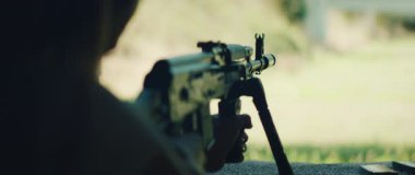 Atış poligonunda çift ayaklı tüfekle nişan alan kişi.