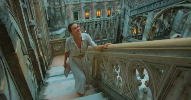 Gülümseyen kadın Milan Katedrali 'nin çatısındaki mermer merdivenleri tırmanıyor..