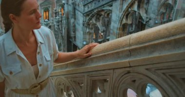 Beyaz elbiseli bir kadın, Milan Katedrali 'nin balüstrasını araştırıyor..