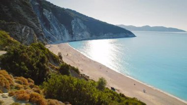 Kefalonya 'da yaz aylarında Myrtos Sahili' ne bakan bir uçurumun tepesinde kutlama yapan kız görülüyor.