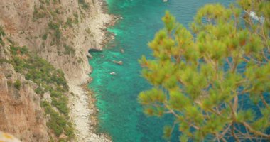 Capri İtalya 'daki sarp kayalıkların altındaki kayalık kıyı şeridi ve zümrüt deniz suları manzarası.