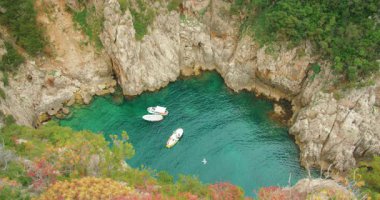Capri Adası 'nın kayalık kayalıklarıyla çevrili küçük zümrüt koyuna demirlemiş tekneler..