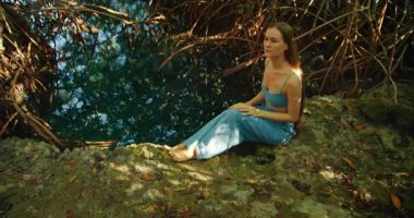 Yucatan Meksika 'daki mangrov ormanlarında kadın sessizce sakin bir şekilde oturur..