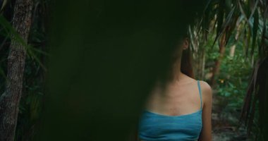 Yeşil yapraklarla gizlenmiş tropikal orman yolunun tadını çıkaran bir kadın..