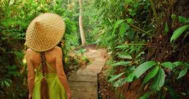 Geleneksel şapkalı kadın Bali 'de orman yolunda taş basamaklarla yürüyor..