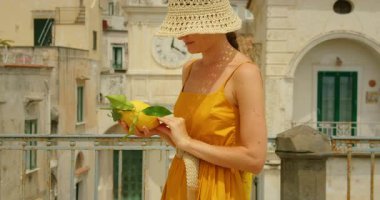 Amalfi kıyısındaki Atrani kasabasının balkonunda büyük limon tutan bir kadının yakın çekimi..