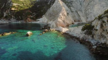 Temiz zümrüt suları Kefalonya 'da yemyeşil dramatik beyaz kayalıkları çevrelemektedir..