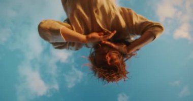 Dansçı kadının mavi gökyüzü arkaplanlı dar açılı görüntüsü.