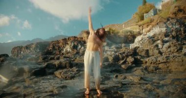Los Gigantes köyü yakınlarında, güneşli mavi gökyüzünün altında, kayalık sahilde dans eden dansçı..