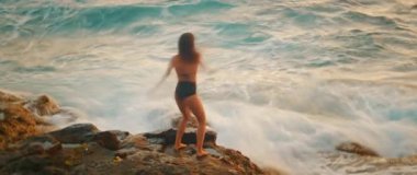 Dişi dansçı, kollarını okyanusun kıyısına kaldırıyor..