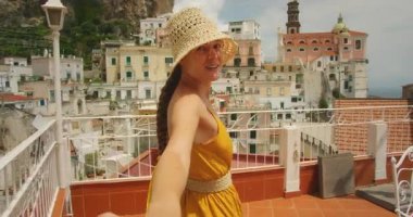 Hasır şapkalı gülümseyen kadın yazın İtalyan terasında yol gösteriyor..