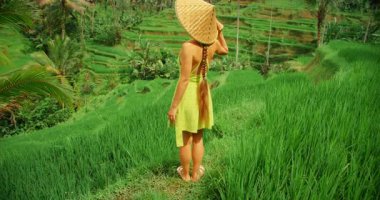 Canlı yeşilliklerle çevrili saman şapkayla Bali pirinç teraslarını keşfeden bir kadın..