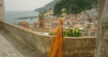 Amalfi manzaralı terasta duran kadın yazın tarihi şehre bakıyor..