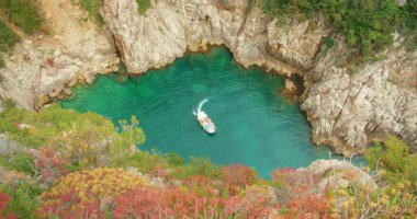 Capri 'deki kayalık kayalıklarla çevrili turkuaz körfeze doğru yol alan bir tur teknesi..