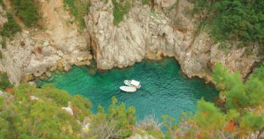 Capri, İtalya 'nın kayalık kayalıkları yakınlarında açık zümrüt deniz sularında yüzen teknelerle dolu bir koy..