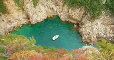 Capri turu sırasında kayalık duvarlı tenha turkuaz bir körfezde yüzen tekne..