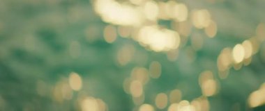 Güneş, ılık bir sabahta, deniz yüzeyinde bokeh desenli yumuşak dalgalarda parlıyor..