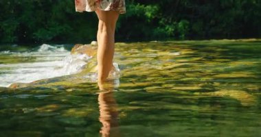 Yaz mevsiminde Hırvatistan ormanlarında Cetina nehrinde yürüyen bir kadın.