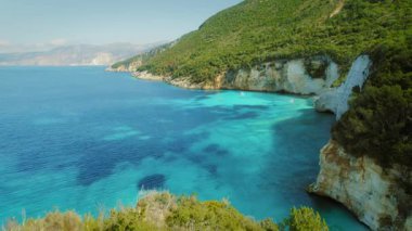 Yunanistan 'ın yaz kıyı şeridi boyunca turkuvaz suları ve uçurumlar üzerinde yürüyen kadınlar.