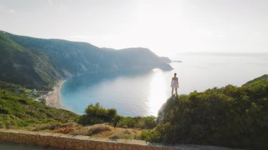 Kefalonya 'daki Petani Sahili' ne bakan bir tepeden yaz günbatımının keyfini çıkaran kadın.