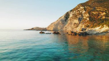 Yaz günbatımında Kefalonia 'daki Petani Sahili' nde kayalık kayalıklar ve berrak turkuaz deniz.