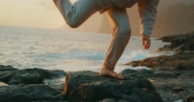 Çıplak ayaklı dansçı kadın volkanik kayanın üzerinde dengede duruyor..