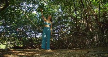 Çıplak ayaklı kadın, yoğun mangrov ormanlarında yürüyüş sırasında yeşil yapraklara uzanır..