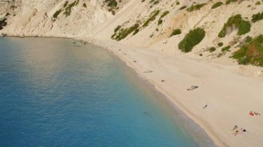 Kefalonia Yunanistan 'da birkaç ziyaretçinin dinlendiği güneşli kayalıkların altındaki kumsal..