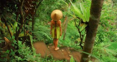 Bali 'deki bereketli tropikal yağmur ormanlarında gülümseyen ve ormanda yürüyen bir kadın..