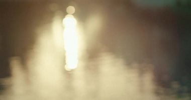 Odak dışı, parıldayan güneş altın saatinde suyun yüzeyinde yansıyor..