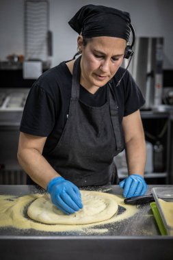 Fırıncı mutfak tezgahında hamur pişiriyor.