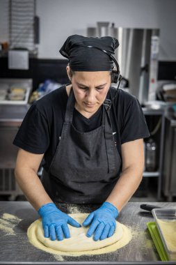 Önlüklü genç adam mutfakta hamur temizliyor.