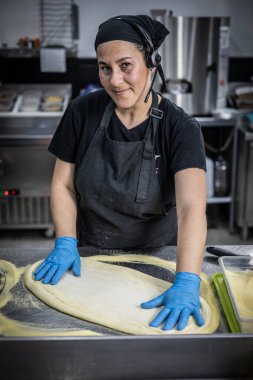 Siyah önlüklü bir kız hamuru pişiriyor.