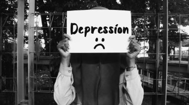 Elinde depresyon mesajıyla yüzünü kapatan kağıt tutan bir kadın ve siyah beyaz arka planda üzgün bir ifade. Hayat hakkında motive edici kelimeler