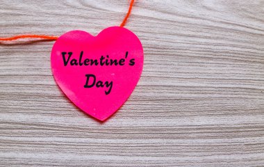 Sevgililer günü kelimeleri kırmızı kalp şeklindeki yapışkan notta gri ahşap arka planda izole edilmiş kırmızı ip var. Sevgililer Günü konsepti
