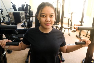 Sportif bir kadın spor salonunda kol ve omuz kasları için egzersiz yapıyor. Pec güverte makinesiyle kol kaslarını çalıştıran kadın