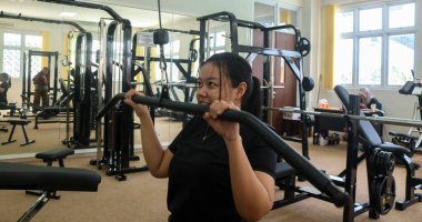 Genç kız spor salonunda Lat Pulldown Machine üzerinde çalışıyor. Kol ve göğüs kası eğitiminde.