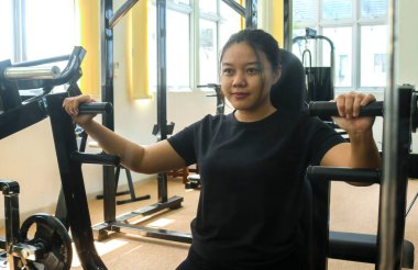 Sportif bir kadın spor salonunda kol ve omuz kasları için egzersiz yapıyor. Pec güverte makinesiyle kol kaslarını çalıştıran kadın