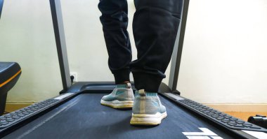 Close up of woman's legs from the side running on a treadmill in a fitness club. Woman running in a gym on a treadmill, exercising concept, cardio exercise, workout, lose weight. clipart