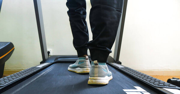 Close up of woman's legs from the side running on a treadmill in a fitness club. Woman running in a gym on a treadmill, exercising concept, cardio exercise, workout, lose weight.