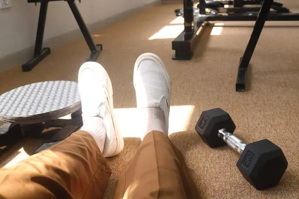 Egzersizden sonra kadınların bacaklarının yanındaki dambılları kapatın. Yerde güneş ışığıyla 5 kilogram halterli spor aleti var. Kol kaslarını çalıştırmak, spor yapmak, kilo vermek için dambıllar.
