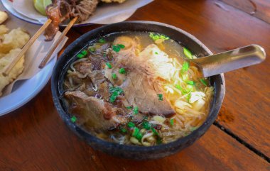 Soto Ayam ve et soto hindistan cevizi kabuğu kabukları içinde ahşap masa üzerinde mendoan aperatifleri, satay ve içecekler. Geleneksel Endonezya çorbası temel olarak et, tavuk ve sebzelerden oluşur..