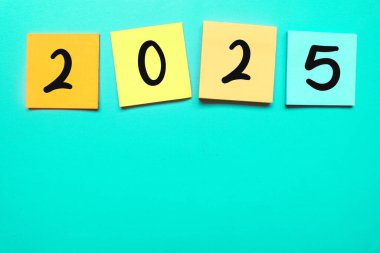 Renkli yapışkan notla 2025 kelime. Yeşil arka planda 2025 kelime. Tipografik 2025 ile yeni yıl konsepti. Yeni yıl için motive edici kelimeler: 2025