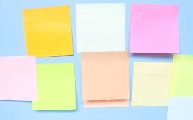 Mavi arkaplandaki renkli boş yapışkan notlar. Boş yapışkan not defteri kağıt kopya alanı koleksiyonu mavi duvara sıkıştı