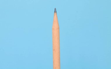 Bir adet klasik açık kahverengi tahta kalem mavi arkaplanda izole edilmiş ve kopyalama alanı var.