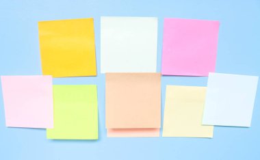 Mavi arkaplandaki renkli boş yapışkan notlar. Boş yapışkan not defteri kağıt kopya alanı koleksiyonu mavi duvara sıkıştı